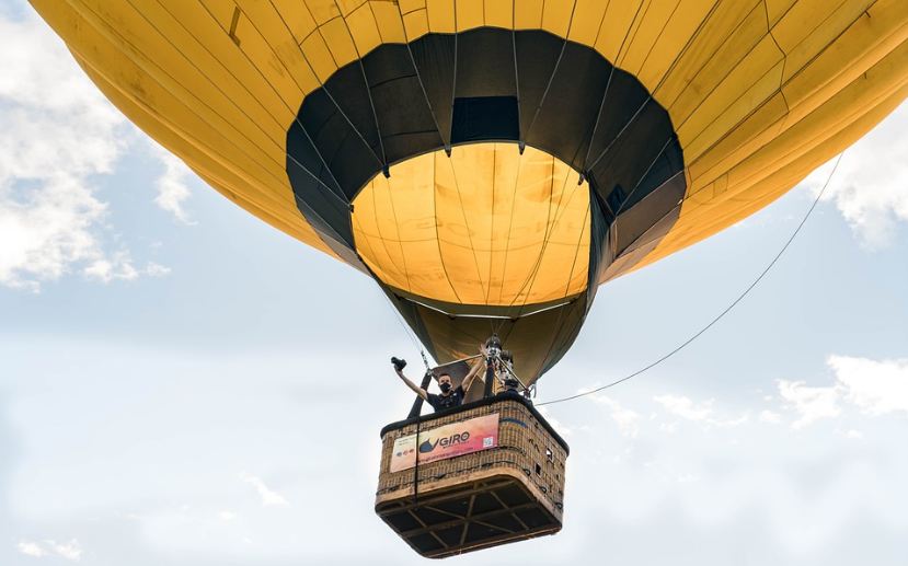 hot air balloon on the air, a man with a camera posing on the hot air balloon