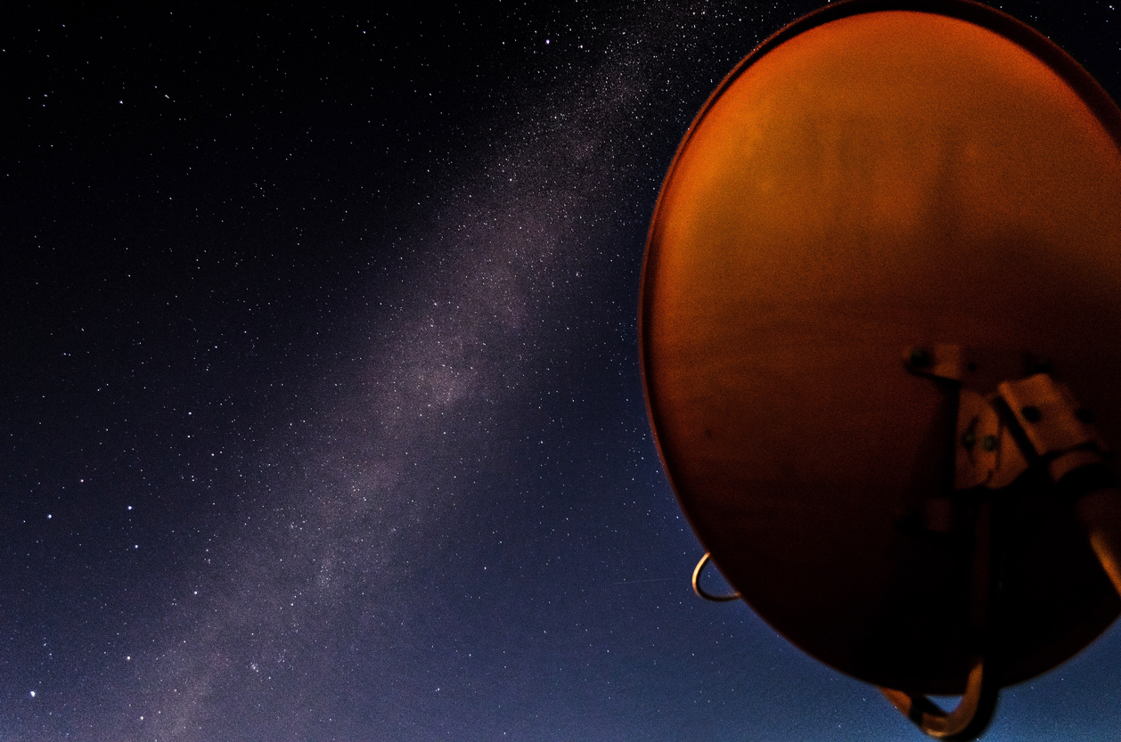 Orange Satellite Dish TV Antenna at night with a milkyway background