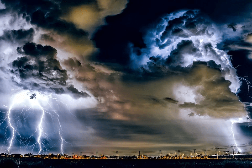 Night lights from the buildings and houses in the city, and the night sky with flashes of lightning