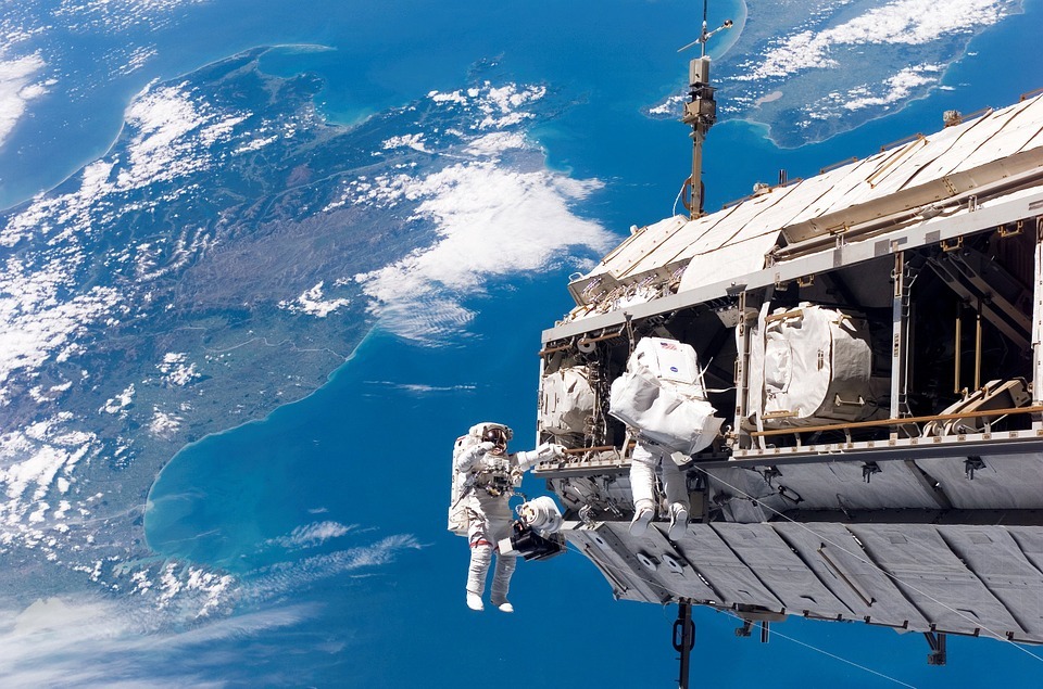 International Space Station orbiting the Earth, different types of clouds, vast blue ocean, land mass, astronauts space walking