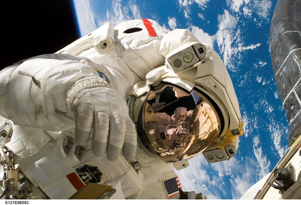 astronaut floating over the earth, small part of the space station on the side