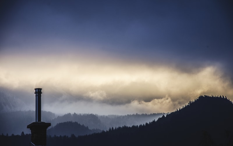 A lighthouse on a mountain under a cloudy sky