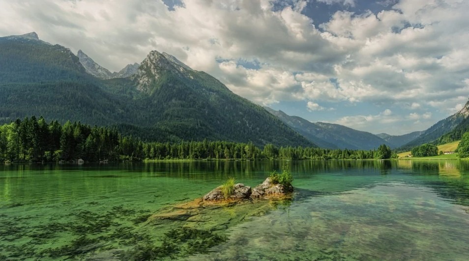 a crystal-clear lake, mountain, and clouds on a clear sky