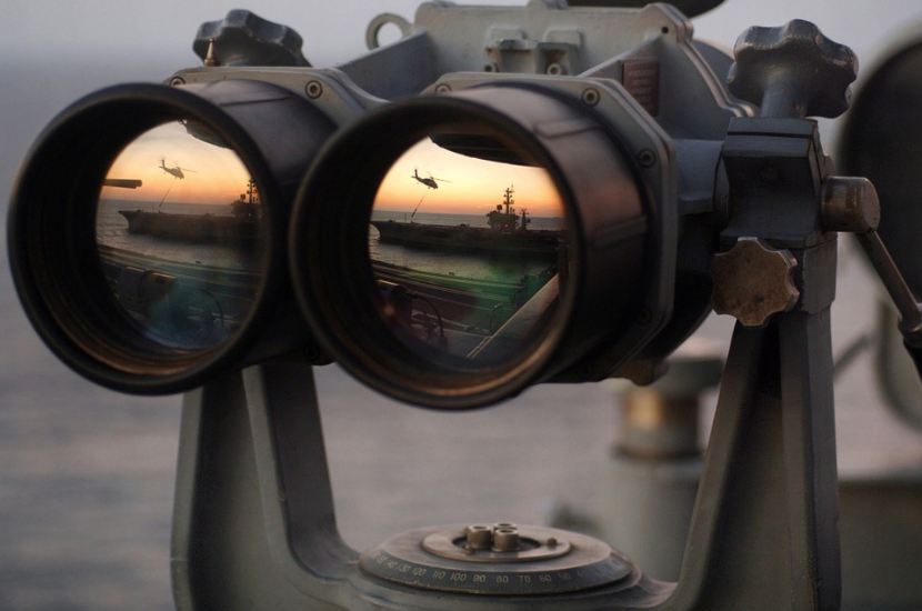 binoculars on a mount, boat, aircraft, and port reflected on the lenses