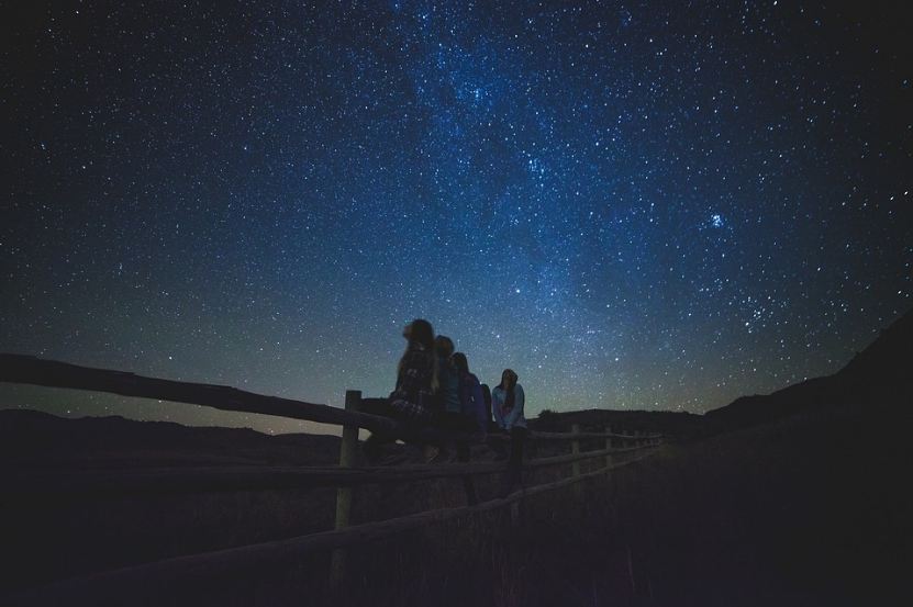 people sitting on the fence, people staring at the sky, myriad stars, blue night sky