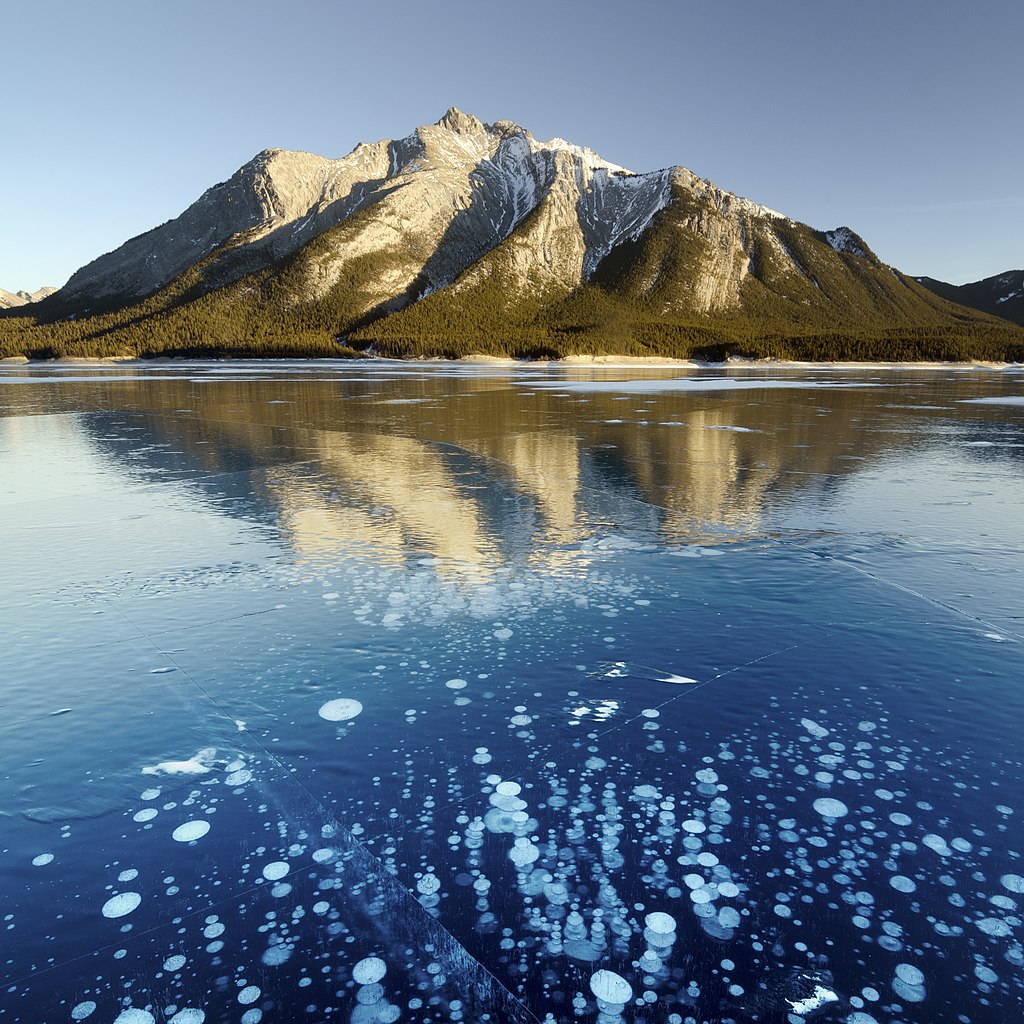 a mountain, and the white frozen bubbles below the frozen lake