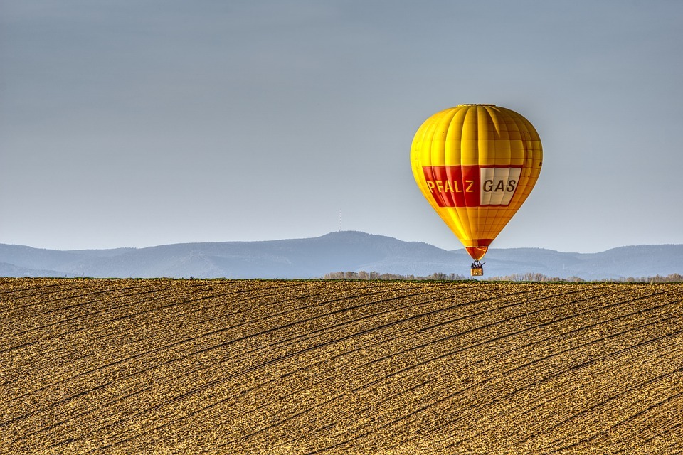 yellow hot air balloon, vast barren field, a mountain at the back