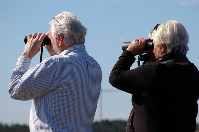 an elderly couple looking through binoculars