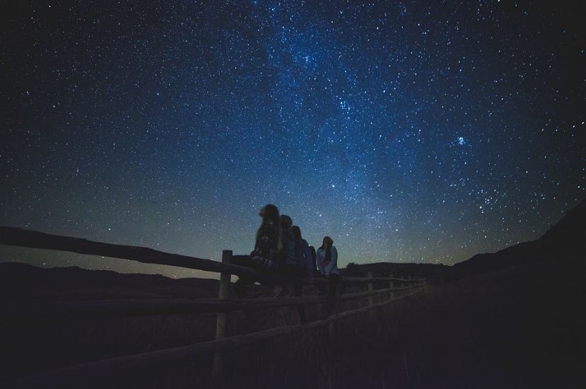 night sky, stars, people stargazing, fence, grass, field